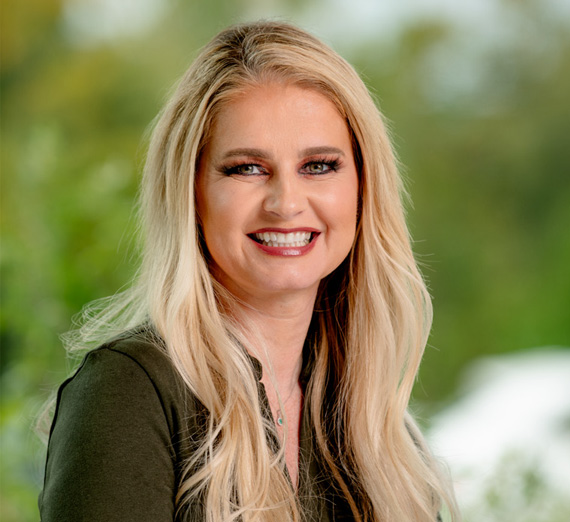 Un grupo de cinco personas está reunido en un pasillo de hospital bien iluminado, sonriendo a la cámara. Dos llevan estetoscopios y ropa médica, uno lleva una sudadera de la Universidad Gonzaga, y los demás visten ropa casual o profesional, representando una mezcla de estudiantes y profesionales de la salud.